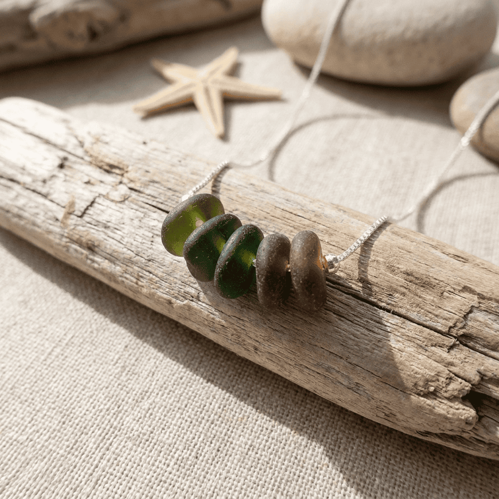 Sea glass beads on driftwood with starfish and stones in the background.