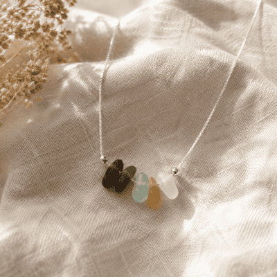 Sunlit seaglass necklace with pastel-coloured sea glass beads on a soft fabric background.
